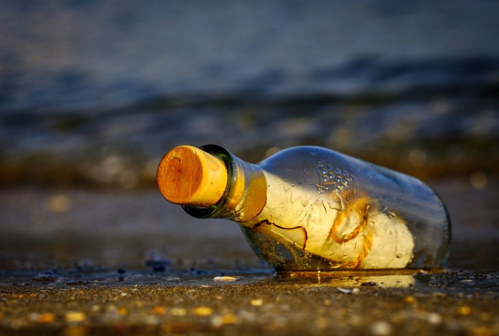 Nærbilde av en flaskepost som har skyllt i land på en strand.