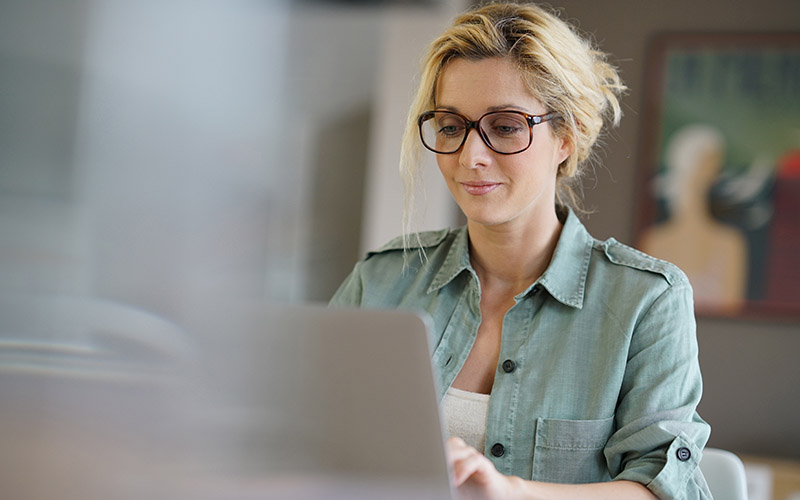 Portrett av blond kvinne som skriver på laptopen.
