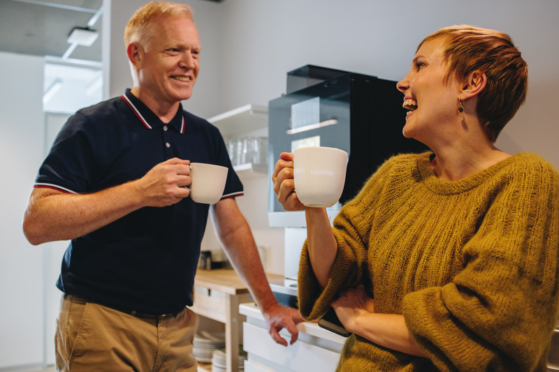 Mann og kvinne som ler og drikker kaffe